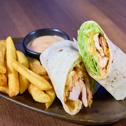 Chicken wrap with lettuce, fries, and dipping sauce on a plate.